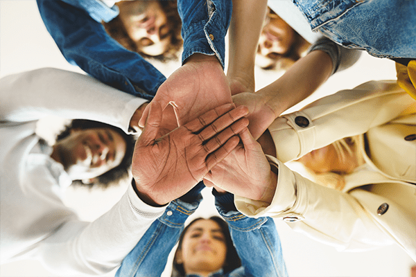 Grupo de pessoas formando um círculo e unindo as mãos